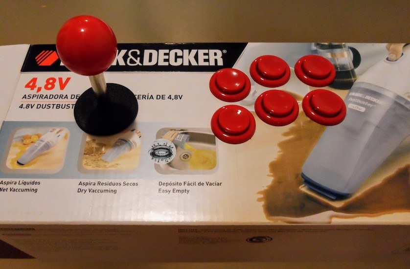 6 plastic red buttons and a joystick with a red ball, mounted on a cardboard box