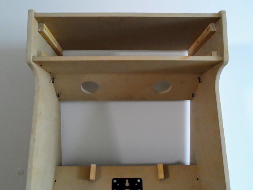 Arcade cabinet with 2 rounded holes for small speakers on the top board