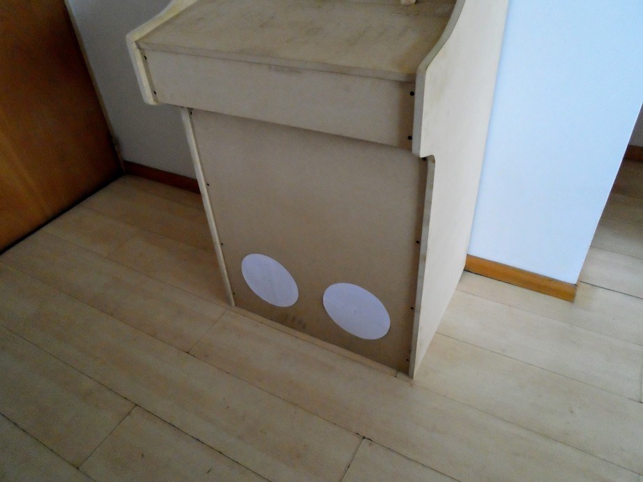 2 rounded papers on the front bottom of the cabinet, where the speakers holes will be