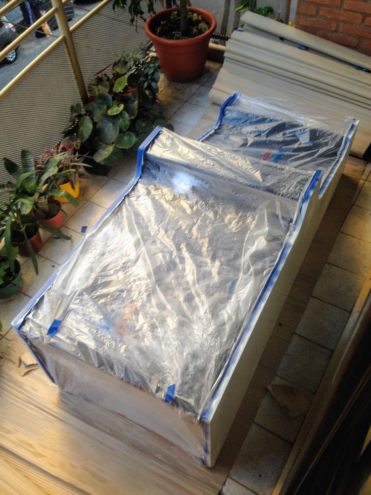 The arcade cabinet on the floor, masked with blue tape and plastic bags